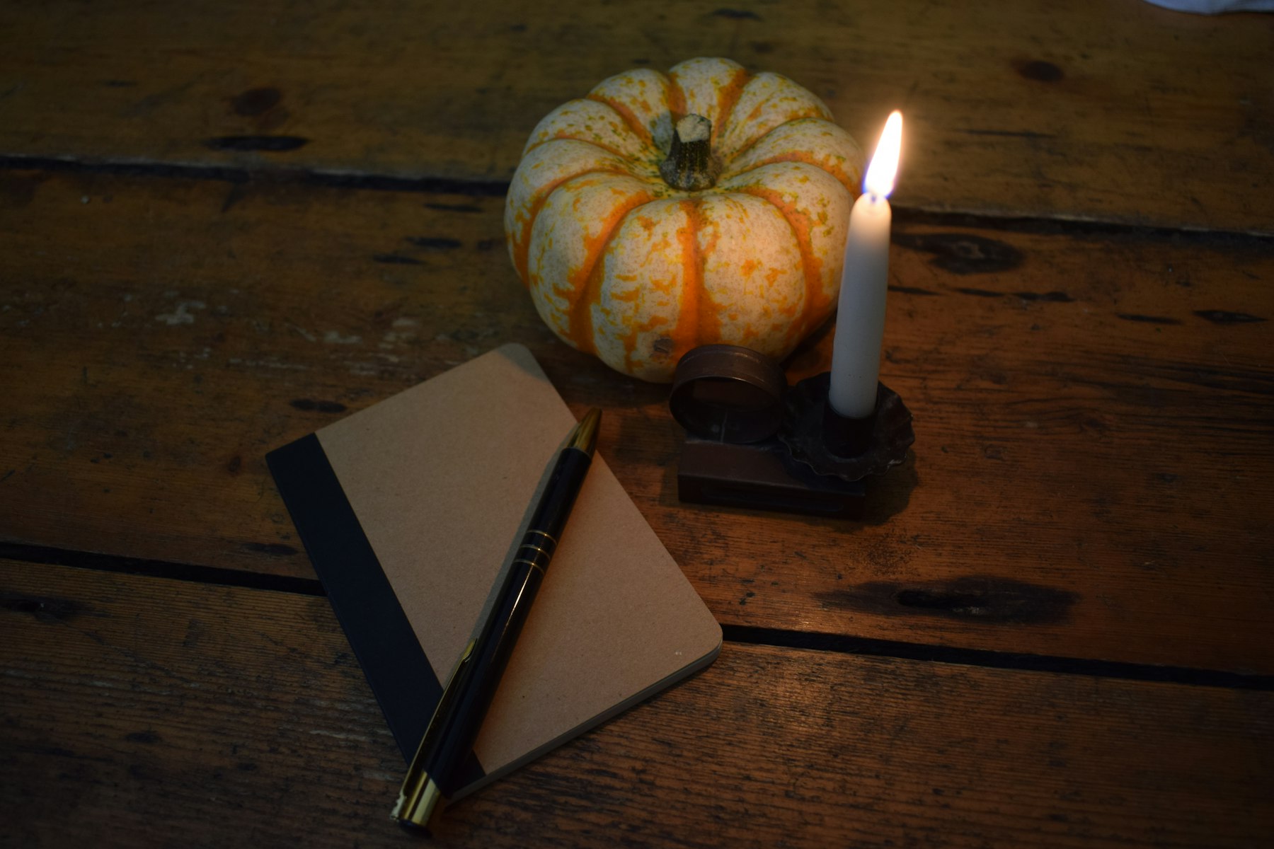 Lit candle and notebook on a wooden table, set up for a 1:1 manifestation coaching session