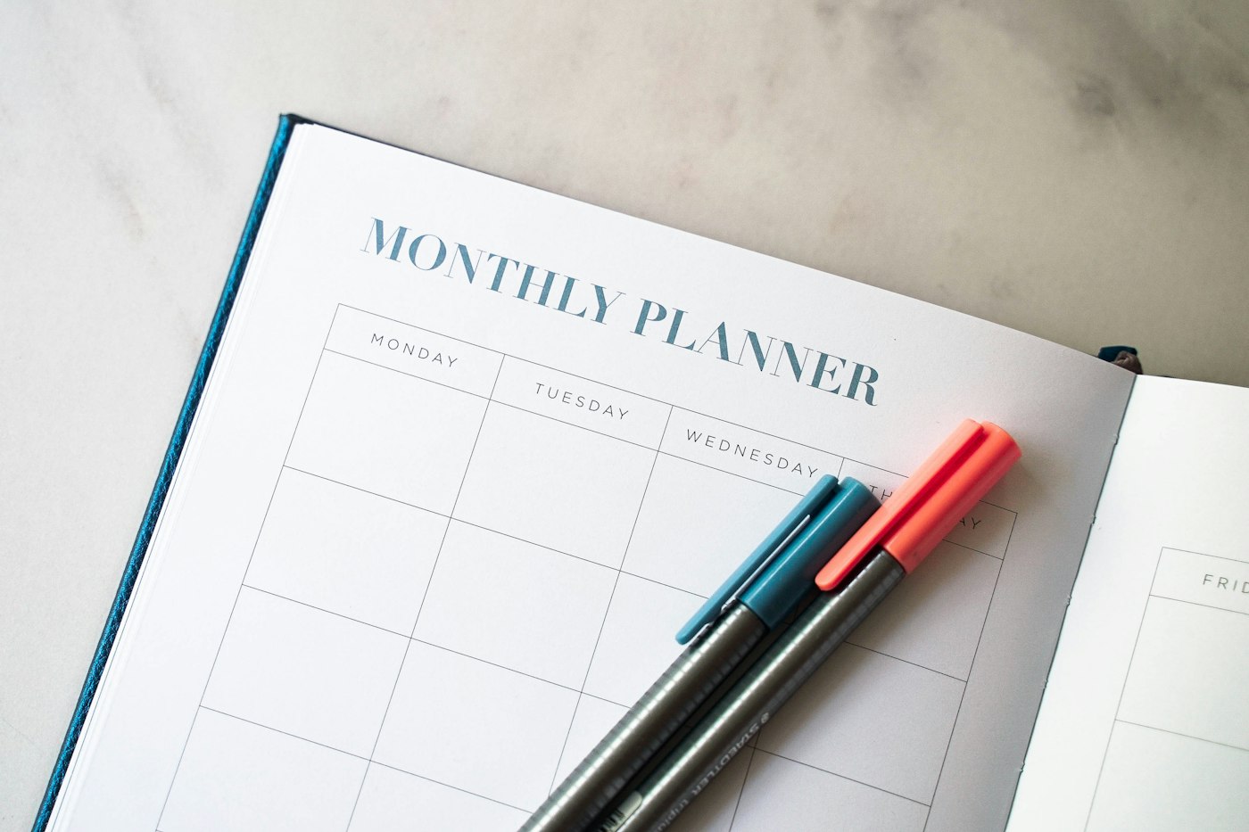 Planner with two pens resting on top, for a money mindset reset workbook