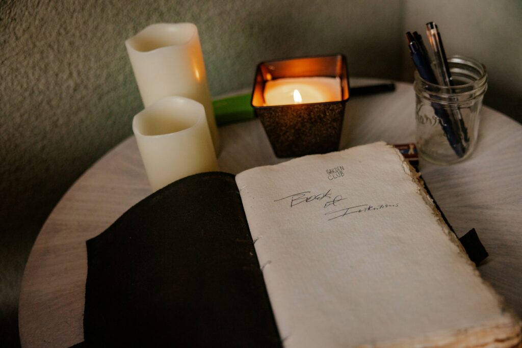 Open journal with handwritten notes beside lit candles, a quiet shadow work journaling moment
