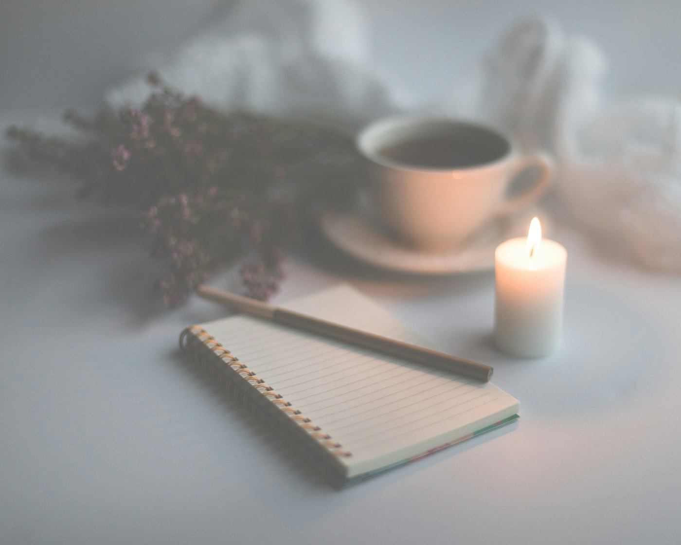 White candle on ruled journal paper beside a ceramic mug, styled for a shadow work journal