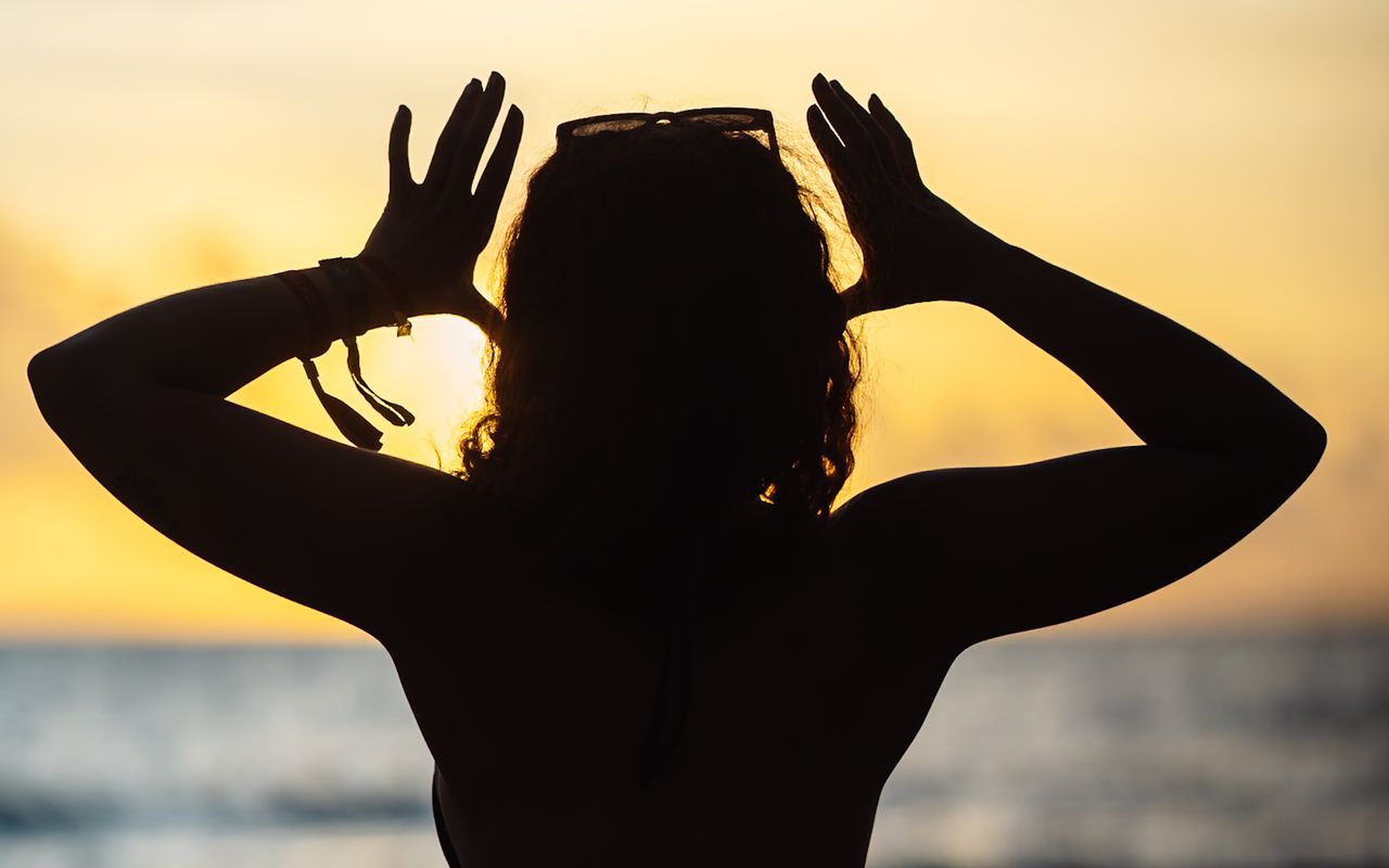 Silhouette of a person at the beach enjoying a calming ocean sunset.